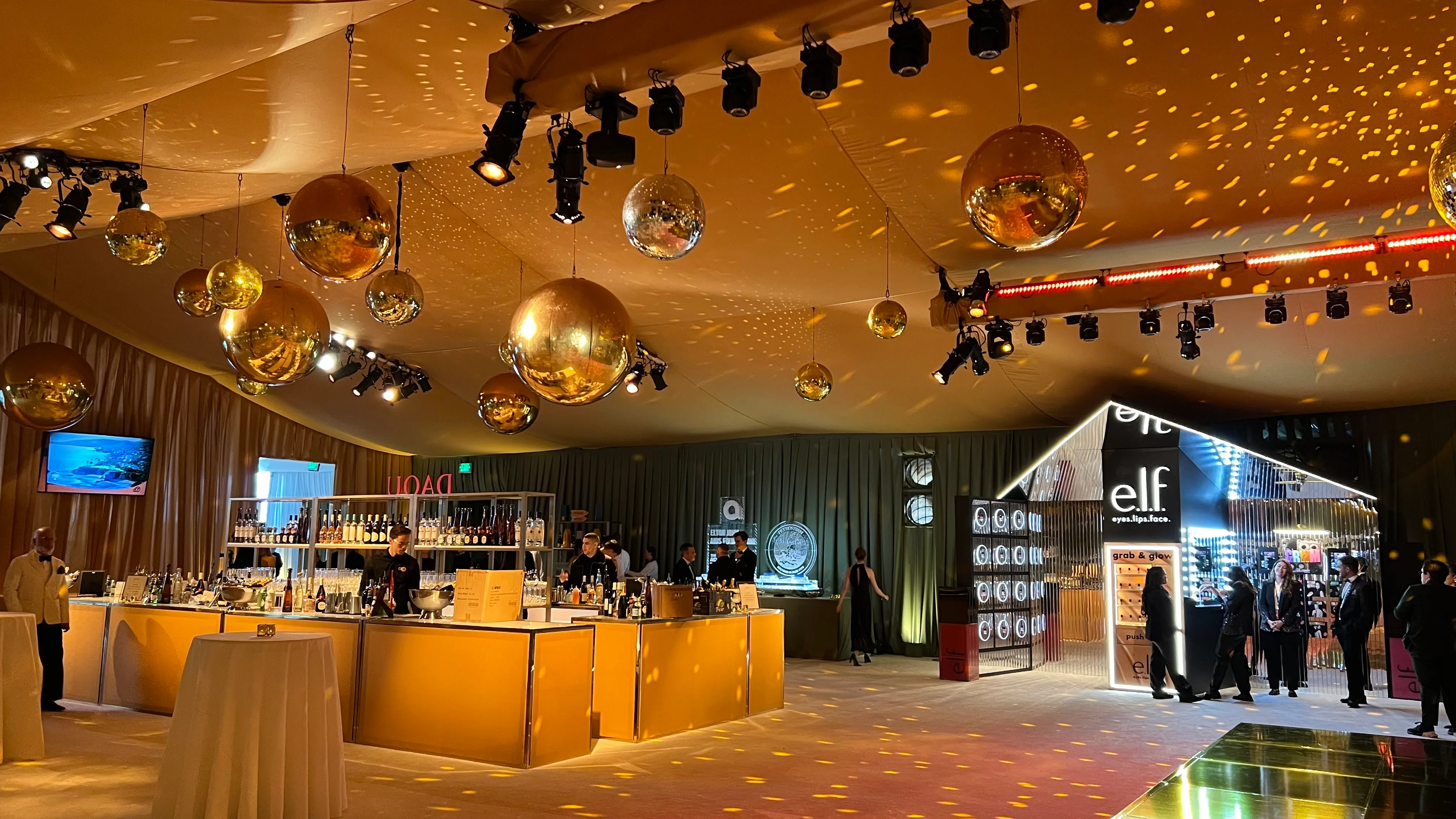Formal gala reception in a draped tent with gold mirror balls and warm textured accent lighting