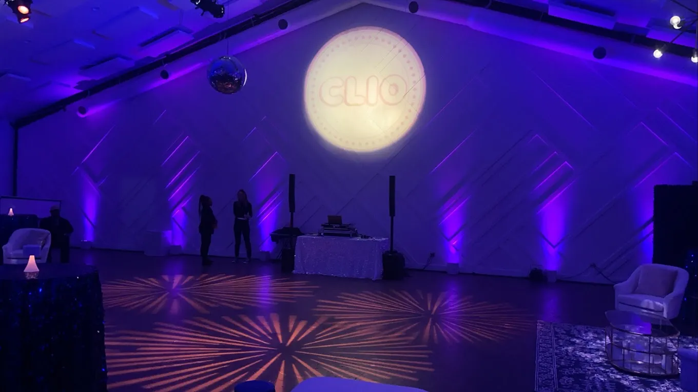 Brand logo projected in crisp light on a venue wall with purple uplighting and patterned floor wash