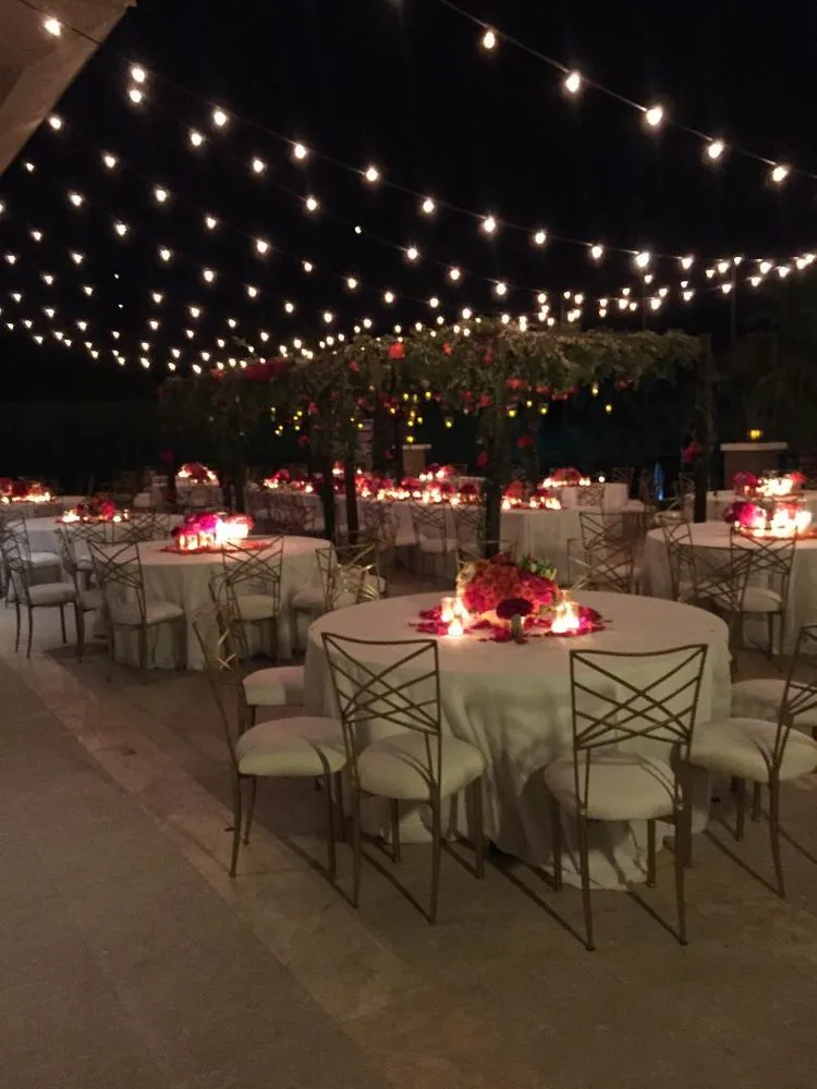 Market string lights over outdoor dinner tables with glowing centerpieces