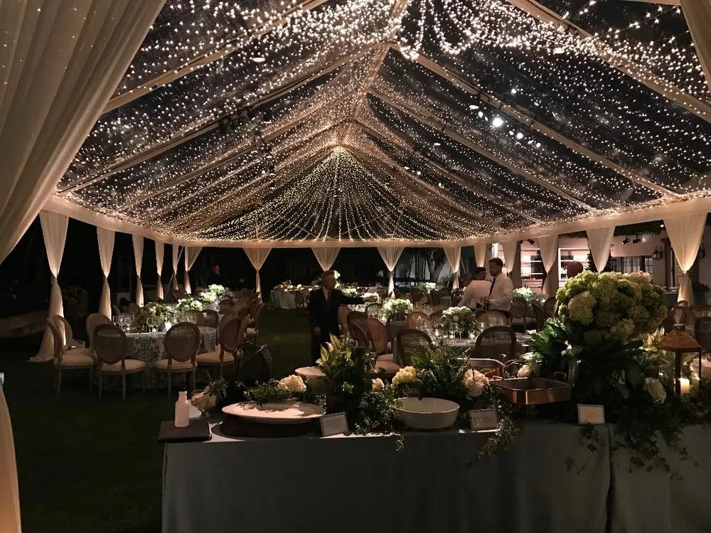 Clear-top tent wedding reception under a full twinkle light canopy